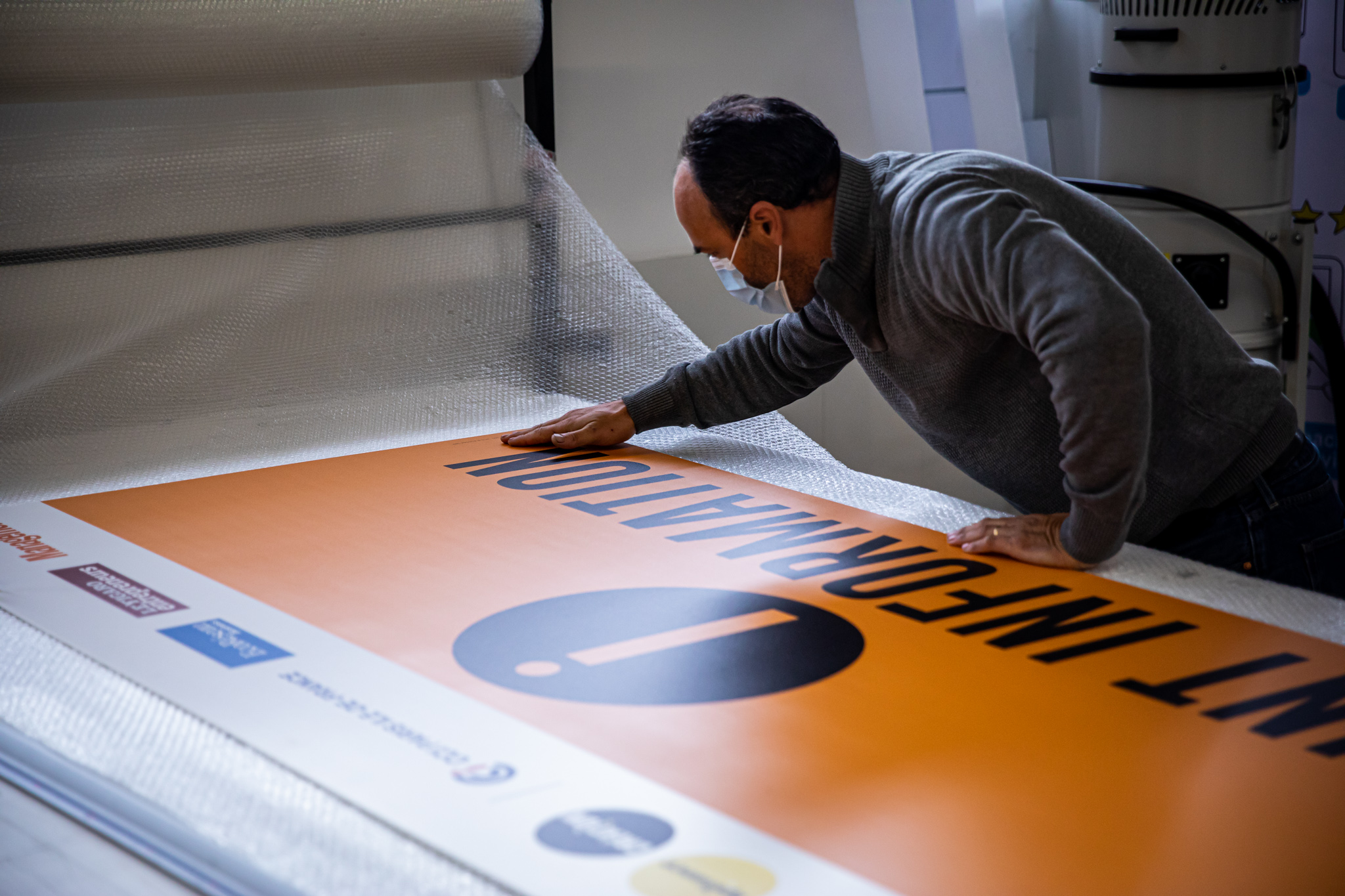 Homme avec masque qui aplatit un panneau orange